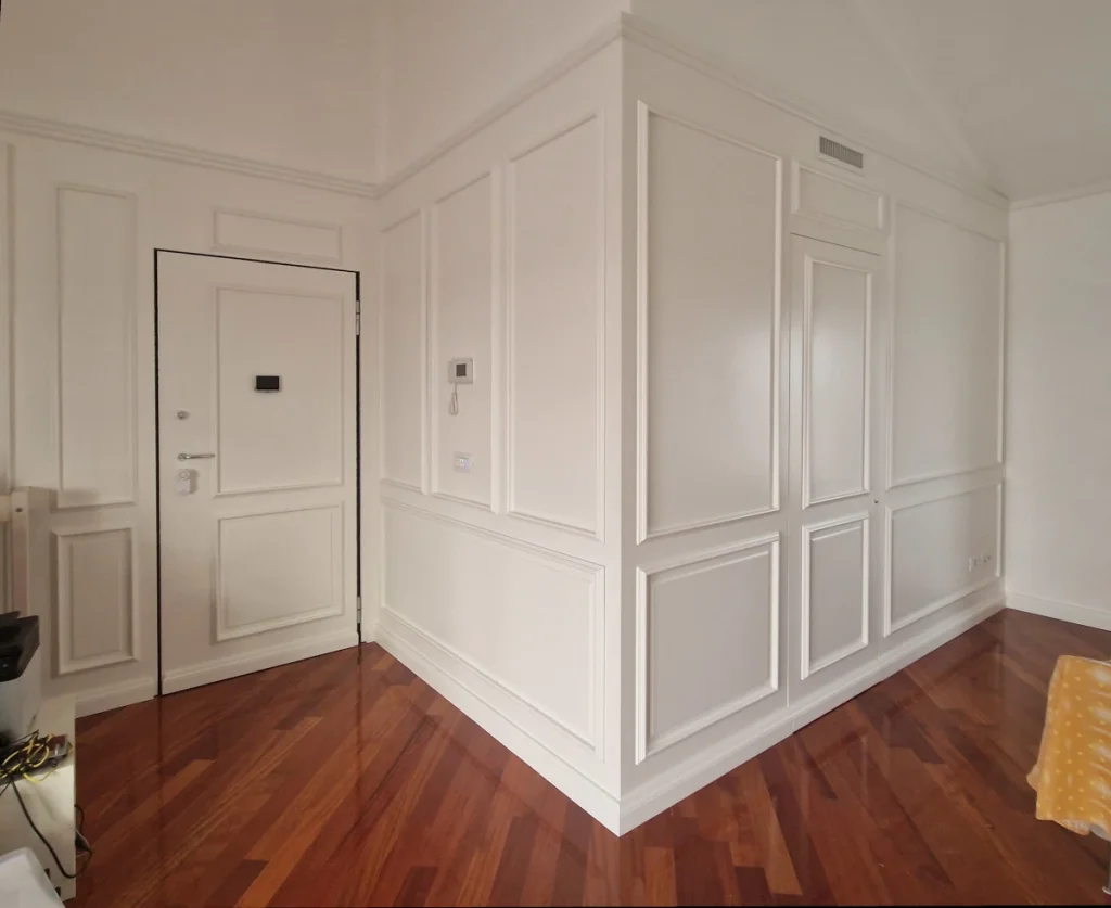 Boiserie laccata bianca con porta a scomparsa e rivestimento portoncino blindato